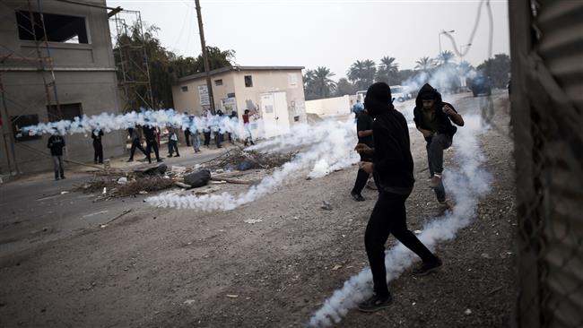 This file photo taken on February 13, 2015 shows Bahraini protesters taking cover from tear gas during clashes with police in village of Bilad al-Qadeem on the outskirts of the capital Manama. (Photo by AFP)