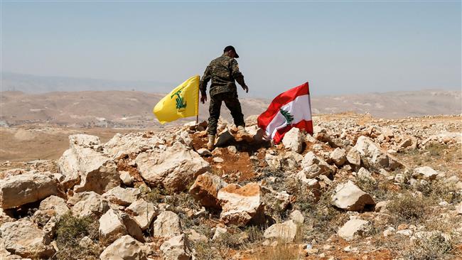 The picture, taken on July 26, 2017, shows a Hezbollah fighter placing a flag of the resistance movement and a Lebanese national flag in a mountainous area around the border town of Arsal. (By AFP)