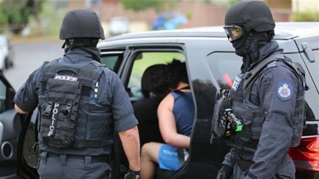 The handout photo, released by the New South Wales Police on December 10, 2015, shows a man (C) being taken into custody during a counter-terrorism operation in Sydney, Australia. (Via AFP)
