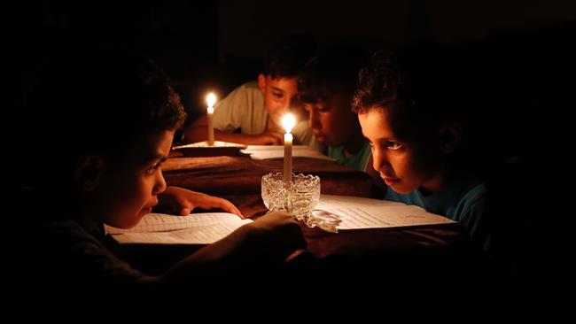 This file photo taken on June 13, 2017 shows Palestinian children at home reading books by candle light due to electricity shortages in Gaza City. (Photo by AFP)