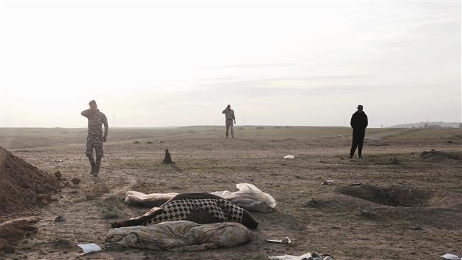 Iraqi forces stand at the site of a mass grave of Daesh victims in Mosul on March 15, 2017. (Photo by AP)