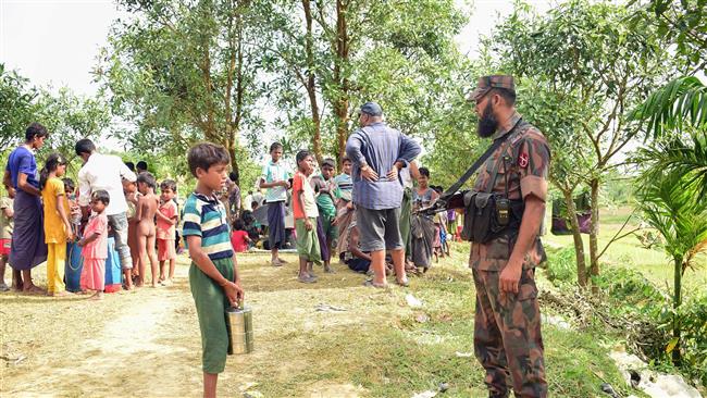 A Bangladeshi border guard talks to a Rohingya boy from Kutupalong refugee camp who brought food for his relatives stranded in the Myanmar-Bangladesh border area near Ukhiya on August 28, 2017. (Photo by AFP)