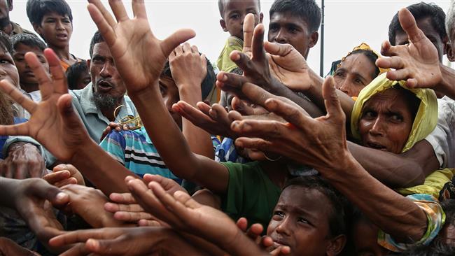 This August 30, 2017 photo shows Rohingya refugees reaching for food aid at Kutupalong refugee camp in Ukhiya near the Bangladesh-Myanmar border. (By AFP)