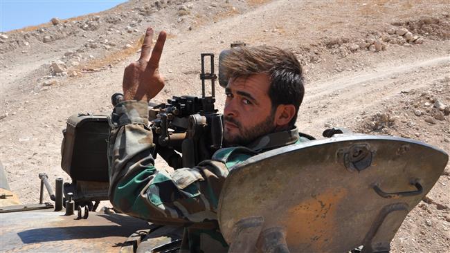A member of pro-government Syrian forces gestures from a tank in the city of Salamiyah, southeast of Hama, on August 19, 2017, during an offensive against the Daesh Takfiri terrorist group. (Photo by AFP)