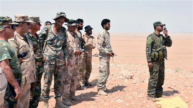 A Syrian soldier (R) speaks on a walkie-talkie as Syrian army troops and pro-government fighters stand next to him near the eastern city of Dayr al-Zawr, Syria, on September 4, 2017. (Photo by SANA)