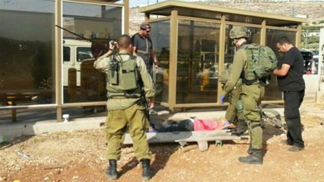 The photo shows Israelis standing over Haitham Hassan Isa Jaradat, a young Palestinian, who was shot and injured by an Israeli soldier on the outskirts of the city of al-Khalil (Hebron) in the occupied West Bank, September 13, 2017.