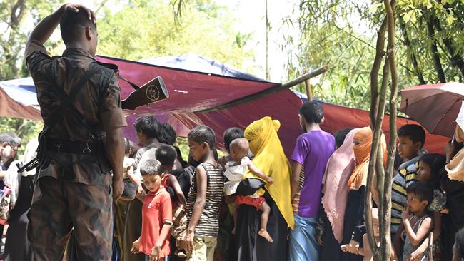 A Bangladeshi border guard, left, watches Rohingya Muslim refugees at the Jalpatoli refugee camp in the no-man
