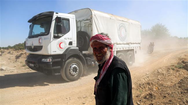 This July 30, 2017 file photo shows a Syrian man smiling as United Nations and Syrian Arab Red Crescent (SARC) convoy trucks arrive in the town of Nashabiyah in eastern Ghouta to deliver aid packages for the first time in five years. (AFP photo)