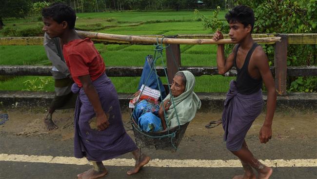 Rohingya Muslim refugees carry an elderly woman along a road near Balukhali refugee camp close to the Bangladeshi district of Ukhia on September 19, 2017. (Photo by AFP)