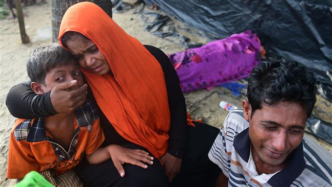 Rohingya refugees sit next to the body of their relative, who died when their boat capsize during their Naf River crossing, in the Bangladeshi city of Teknaf on September 14, 2017. (Photo by AFP)