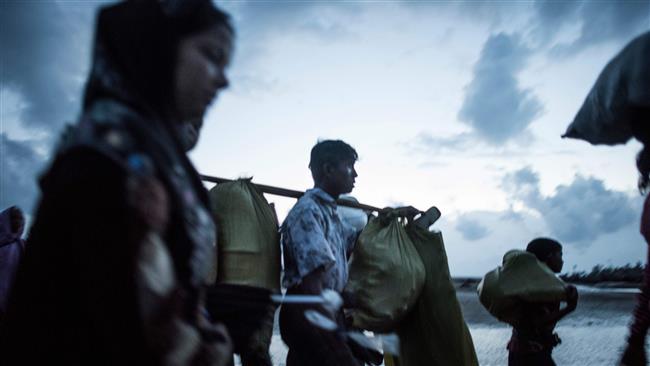 This September 29, 2017 photo shows Rohingya Muslim refugees walking on the shore after crossing the border from Myanmar on the Bangladeshi side of the Naf River in Teknaf. (Photo by AFP)