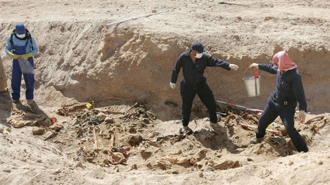 In this file picture, Iraqi workers excavate remains from a mass grave in the desert of the western province of Anbar. (Photo by Reuters)