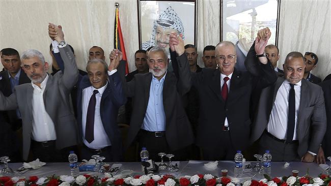 Fatah and Hamas officials hold their hands up during a meeting in Gaza City, October 2, 2017. (Photo by AP)