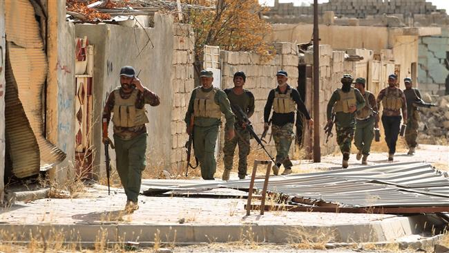 Fighters from the Popular Mobilization Units (Hashd al-Sha’abi) secure a street as troops advance through Hawijah on October 5, 2017, after retaking the city from Daesh Takfiri terrorists. (Photo by AFP)