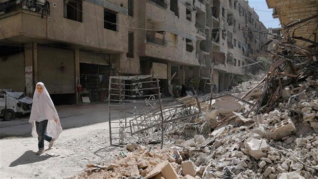 A Syrian girl walks past the rubble of a destroyed building down a street in Ein Tarma, Rif Dimashq Province, Syria, July 19, 2017. (Photo by AFP)