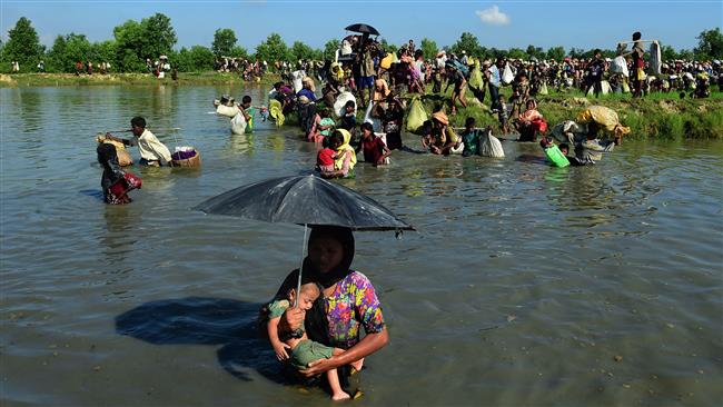 A Rohingya woman carries a child across a shallow canal after crossing the Naf River as they flee violence in Myanmar to reach Bangladesh in Palongkhali near Ukhia, October 16, 2017.