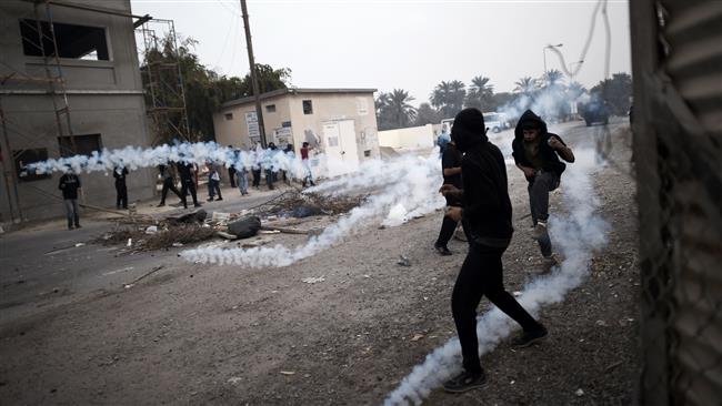 The photo taken on February 13, 2015 shows Bahraini protesters taking cover from tear gas during clashes with regime forces on the outskirts of the capital Manama. (Photo by AFP)