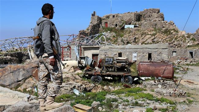 A picture taken on November 14, 2017 shows an armed Yemeni man looking at a communications tower that was destroyed in Saudi air strikes on the city of Ta’izz. (Photo by AFP)
