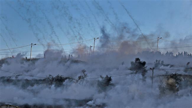 A field in the West Bank city of Ramallah is covered with tear gas fired by Israeli troops during clashes with Palestinian protesters on December 8, 2017. (AFP photo)