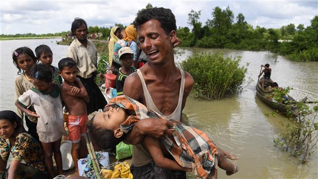 A Rohingya refugee reacts while holding his dead son after crossing the Naf River from Myanmar into Bangladesh, in Whaikhyang, on October 9, 2017. (Photo by AFP)