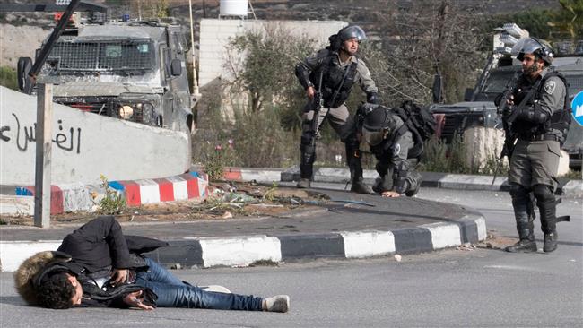 A Palestinian man clutches his stomach after being shot by Israeli soldiers over an alleged stabbing attack in the occupied West Bank town of al-Bireh on December 15, 2017. (Photo by AFP)