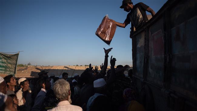 This picture taken on December 4, 2017 shows an aid worker handing out blankets from a truck to Rohingya refugees in the Kutupalong refugee camp in Bangladesh.
