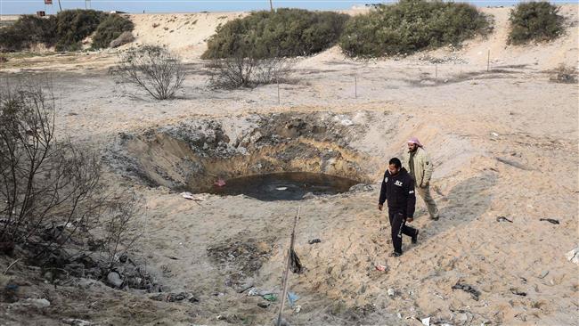 Palestinians walk past the site of an Israeli airstrike targeting in Khan Yunis town in the southern Gaza Strip in December 13, 2017. (Photo by AFP)