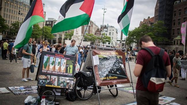Tourists look at a BDS stand with photos and Palestinian flags at the Dam Square in central Amsterdam, the Netherlands, June 24, 2016. (Photo by Flash90)