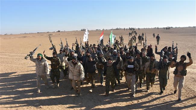 Members of Popular Mobilization Units (Hashd al-Sha’abi), celebrate after Iraqi Prime Minister Haider al-Abadi declared victory in the war against Daesh Takfiri terrorist group, about 80 kilometers (about 50 miles) along the Iraqi-Syrian border west of the border town of al-Qaim on December 9, 2017. (Photo by AFP)
