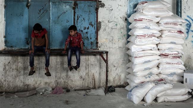 Palestinian children sit by sacks of food aid provided by the United Nations Relief and Works Agency for Palestine Refugees in the Near East (UNRWA), in the town of Rafah, in the Southern Gaza Strip, August 22, 2017. (Photo by AFP)