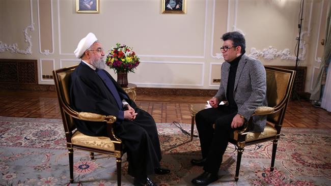 This January 22, 2018 photo provided by the Iranian Presidency shows Iranian President Hassan Rouhai (L) speaking during a live interview with the national broadcaster in his office in Tehran.