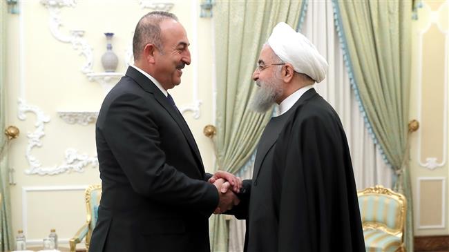 Iranian President Hassan Rouhani (R) and Turkish Foreign Minister Mevlut Cavusoglu shake hands prior to their meeting in Tehran on February 7, 2018. (Photo by president.ir)