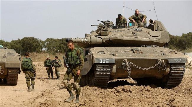 In this file picture, Israeli soldiers stand guard with their tank along the border between the Gaza Strip and the occupied Palestinian territories. (Photo by the Times of Israel)