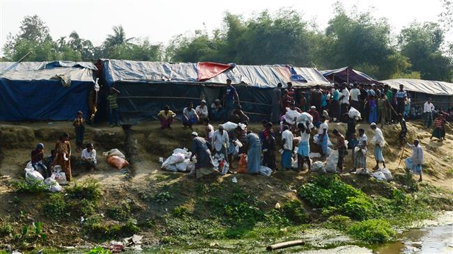 Rohingya refugees collect relief material next to a settlement near the no man’s land area between Myanmar and Bangladesh. (File photo by AFP)