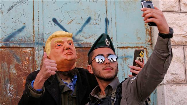An Israeli soldier takes a selfie with an Israeli settler dressed in a mask of US President Donald Trump in the occupied West Bank town of Hebron (al-Khalil), on March 01, 2018. (Photo by AFP)