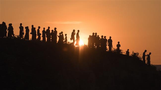 In this file photo, taken on November 26, 2017 Rohingya Muslim refugees walk down a hillside in the Kutupalong refugee camp in Cox’s Bazar, Bangladesh. (By AFP)