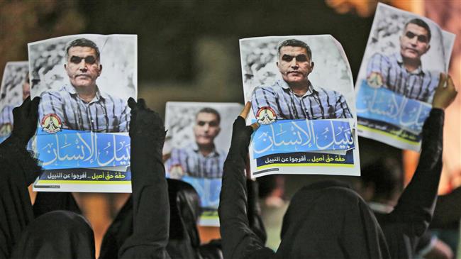 The file photo shows Bahraini anti-government protesters hold up images of detained human rights activist Nabeel Rajab during an anti-government protest outside his home in Bani Jamra, Bahrain.