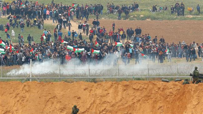 A picture taken on March 30, 2018 from the southern Israeli kibbutz of Nahal Oz across the border from the Gaza Strip shows Palestinians participating in a tent city protest commemorating Land Day, with Israeli soldiers seen below in the foreground. (Photo by AFP)