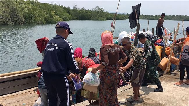 This handout photo released and taken by the Royal Thai Army on April 1, 2018, shows a member of the Royal Thai Navy rescue team assisting Rohingya refugees to board their wooden boat after a brief stop on an island in Krabi province. (Photo by AFP)