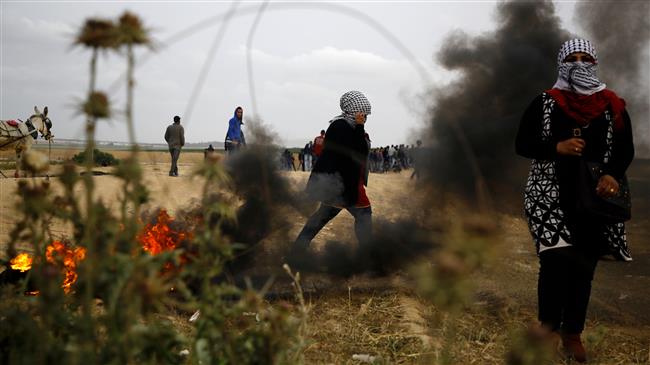 Palestinian women, with their faces covered in traditional Palestinian keffiyeh scarves, are seen during clashes with Israeli forces following a protest east of Gaza City, April 3, 2018. (Photo by AFP)