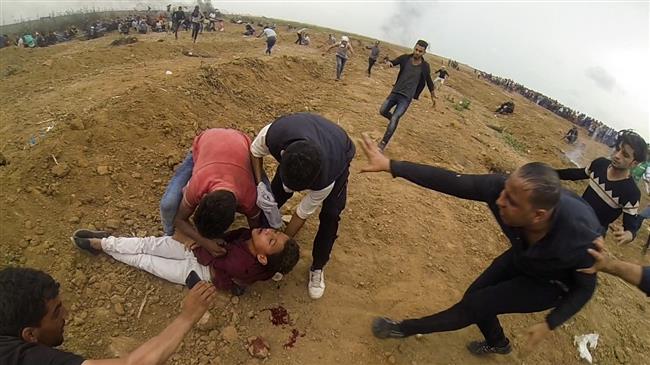 A picture taken on April 20, 2018 shows Palestinians gathering around the body of 15-year-old Mohammed Ibrahim Ayoub after he was shot and killed by Israeli forces during clashes along the Gaza fence in the northern Gaza strip. (Photo by AFP)