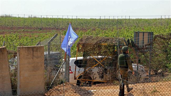 A picture taken on April 8, 2018 from the southern Lebanese village of Kfar Kila on the border with Israeli-occupied territories shows an Israeli soldier walking next to a UN flag along the border. (AFP photo)