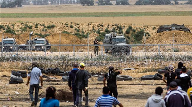 An Israeli soldier, seen in the background, takes aim at Palestinian protesters from across the fence during clashes along the border with the Gaza Strip east of Khan Yunis on May 4, 2018. (Photo by AFP)