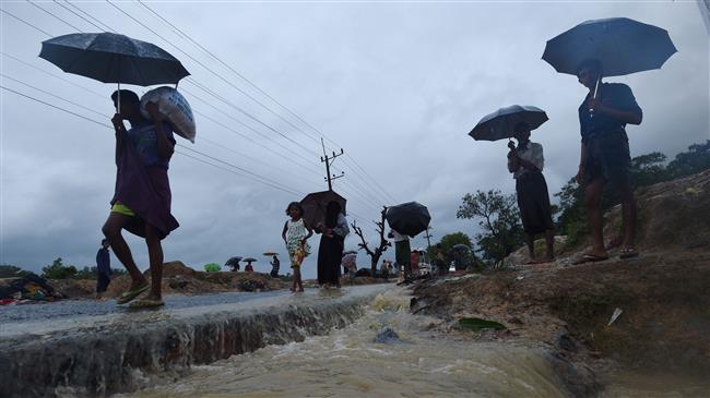 In this photo taken on September 19, 2017, Rohingya refugees walk in the rain at Kutupalong refugee camp in the Bangladeshi locality of Ukhia. (Photo by AFP)