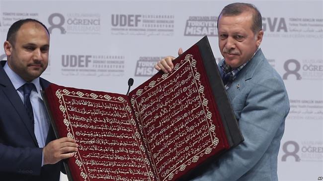 Turkey’s President Recep Tayyip Erdogan (R) receives a copy of the Qur’an at an international students’ meeting in Istanbul, Turkey, on May 16, 2015. (Photo by AP)