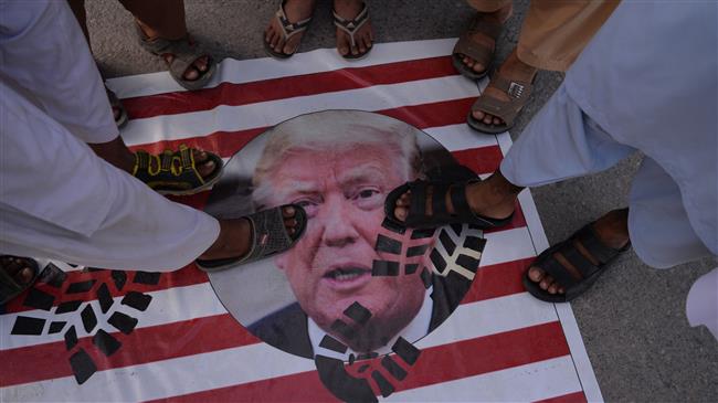 Pakistani protesters stand on a US flag with printed an image of US President Donald Trump during a protest in Islamabad on May 16, 2018. (Photo by AFP)