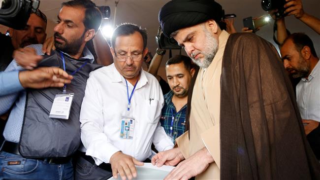 Iraqi cleric Moqtada al-Sadr (C-R) votes through an electronic counting machine at a polling station in the central holy city of Najaf on May 12, 2018. (AFP photo)