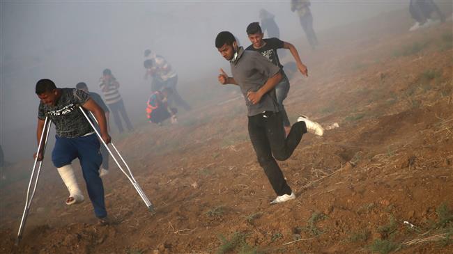 Palestinians run for cover from tear gas shot by Isreali forces during a demonstration along the Gaza Strip’s border, May 25, 2018. (Photo by AFP)