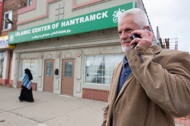 Arif Huskic makes a call in front of the Islamic Center of Hamtramck mosque. Photograph: Bryan Mitchell for the Guardian