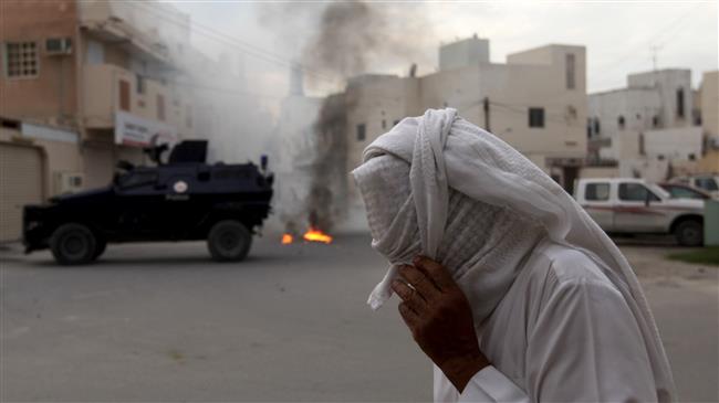 A Bahraini man covers his face against tear gas during clashes between anti-regime protesters and riot police firing tear gas and shotguns in Diraz, Bahrain, on January 29, 2014. (Photo by AP)